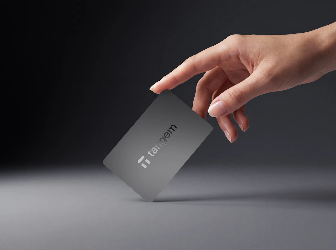 Hand picking up a matte black Tangem card
